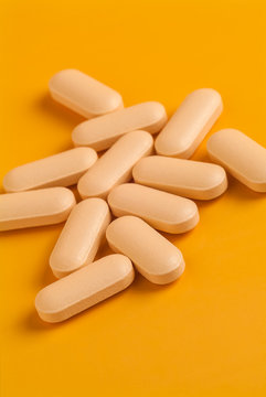 Orange vitamin pills on an orange background