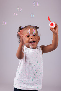 Little African American girl playing with soap bubbles