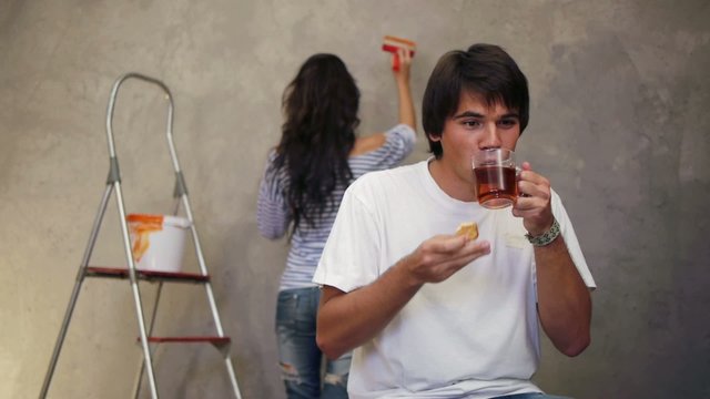 Attractive man drinking tea while his wife working