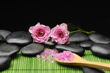 herbal salt in spoon with rose stones on green mat