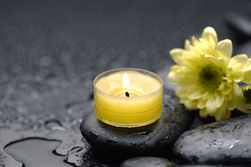burn yellow candle with Daisy flowers on pebbles