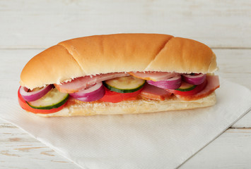 Small sandwich with deli meats and vegetables on a white napkin