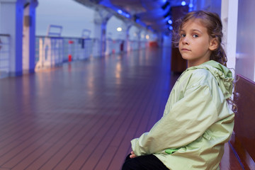 Little girl sitting on bench on deck of passenger ship