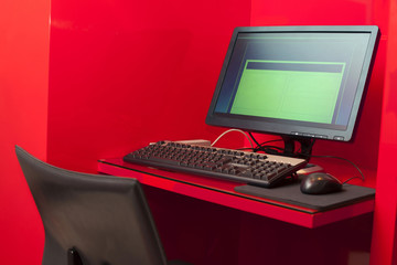 Monitor keyboard mouse mat on table in red room