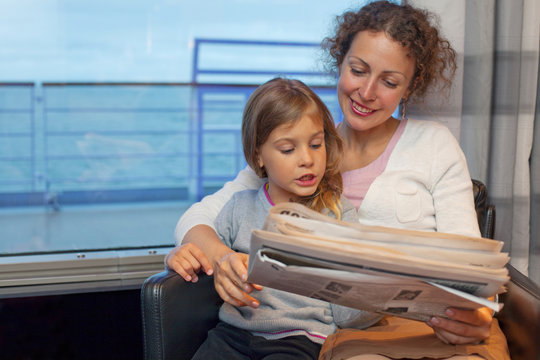 Mother daughter reading newspaper in cabin of passenger ship