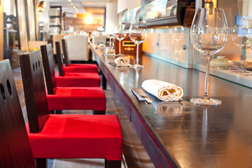 Red chairs near bar with glasses, towel in sushi restaurant