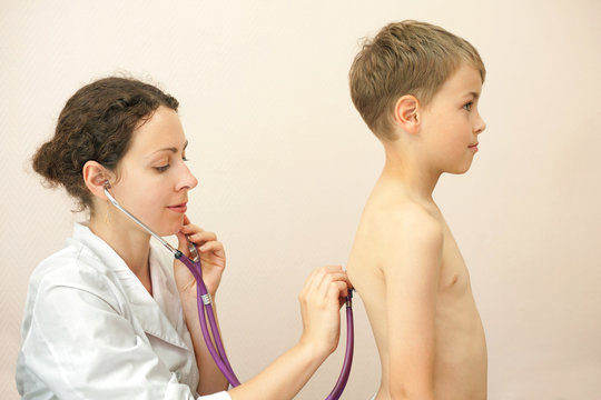 Doctor listens to lungs of little boy with stethoscope