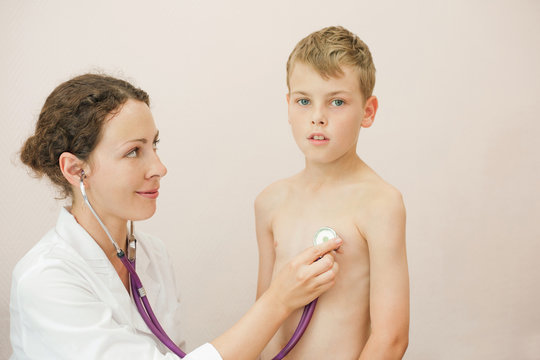 Doctor listens to lungs of boy with stethoscope looks at him
