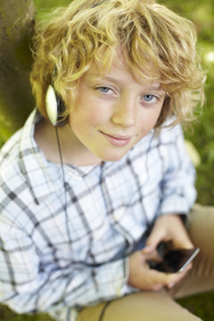 Boy Listening To MP3 Player Outdoors
