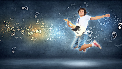 Fototapeta na wymiar young man playing on electro guitar and jumping