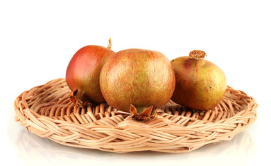 unripe pomegranates on wicker mat isolated on white