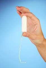woman's hand holding a clean cotton tampon