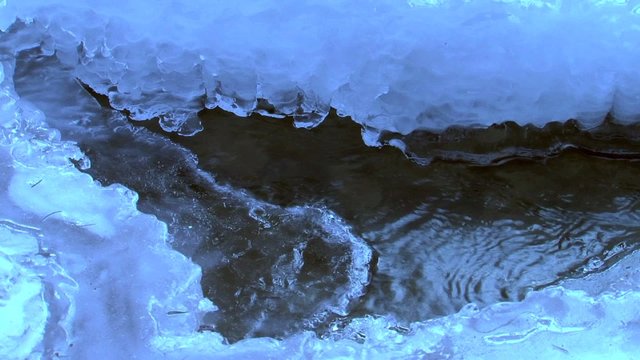 Wasser fliesst im Eis des zugefrorenen Baches