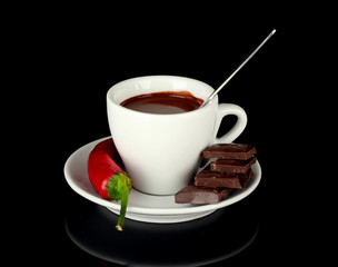 white cup with hot chocolate and chili pepper isolated on black