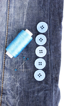 Colorful sewing buttons with thread on jeans