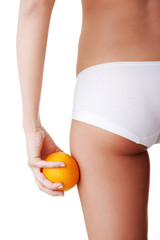 Girl holding an orange next to the buttocks is isolated