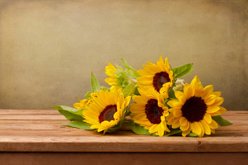 Obraz premium Sunflowers on wooden table against grunge background