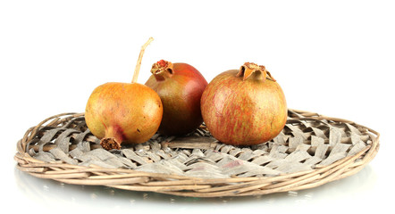 unripe pomegranates on wicker mat isolated on white