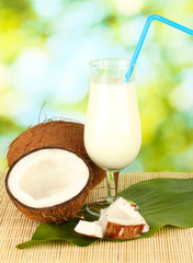 glass of coconut milk and coconuts on green background close-up