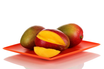 Ripe appetizing mango on red plate isolated on white