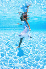 Underwater woman with white dress in swimming pool