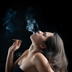 Obraz premium Woman smoking cigar against dark background. Fashion photo