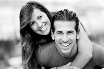 Smiling young man piggybacking his pretty girlfriend