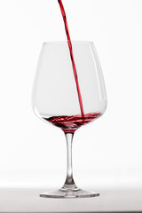 Rotwein wird schwungvoll in ein Rotweinglas gegossen