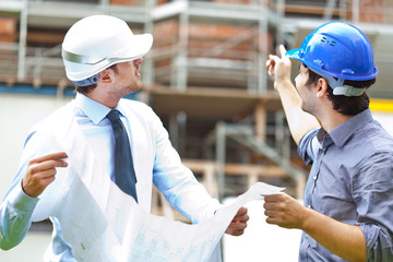 Engineer showing something to his partner at building site