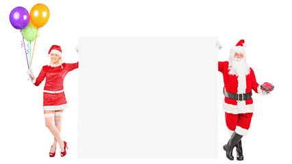 Male and female Santa Clauses holding a blank panel