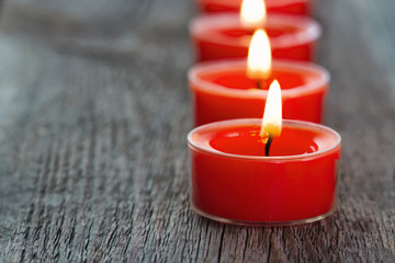 Red burning candles on a wooden background
