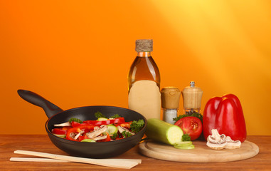 frying pan with vegetables on red background
