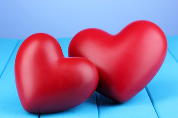 Decorative red hearts on blue wooden table on blue background