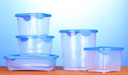 Plastic containers for food on wooden table on blue background