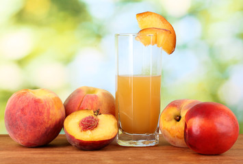Ripe peaches and juice on wooden table on natural background