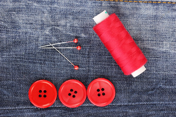 Colorful sewing buttons with thread on jeans closeup