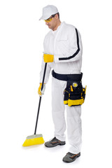 construction worker in white overalls sweeping with a broom on w