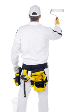 construction worker in white overalls with paint roller paint th