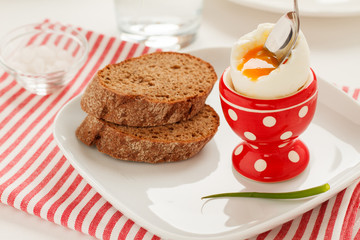 Soft-boiled egg in a red egg cup and whole grain bread
