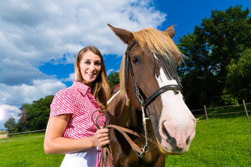Obraz premium Junge Frau reitet auf dem Pferd auf der Wiese