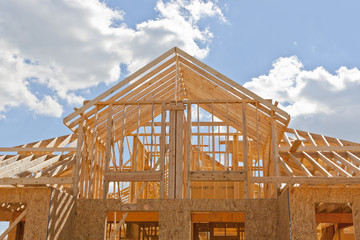 New residential construction home framing against a blue sky