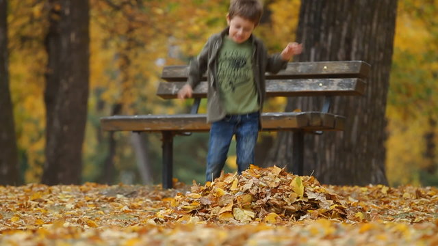 Seven year old boy throws autumn leaves and running