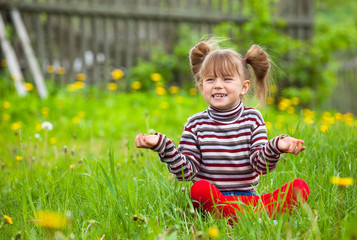 Lovely emotional five-year girl sitting in grass.