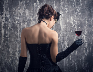 young woman in carnival mask and a glass of red wine.