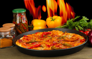 Tasty pepperoni pizza in pan with vegetables on flame