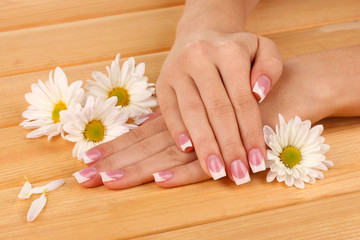 Obraz na płótnie Canvas Ręce kobiety z french manicure i kwiaty
