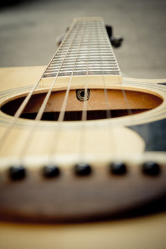 Macro shot down the fretboard of acoustic guitar with shallow de