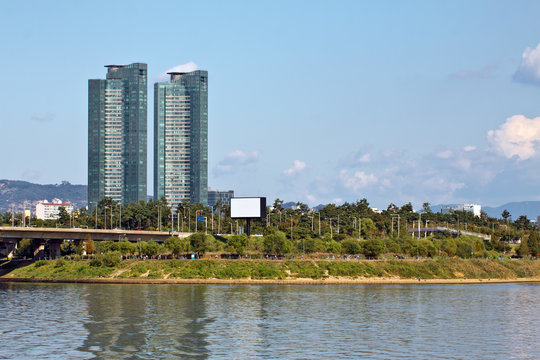 Two modern buildings and green park over river