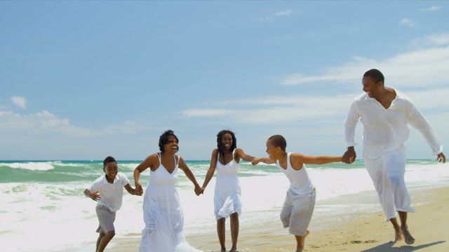 African American family together playing and laughing by ocean 