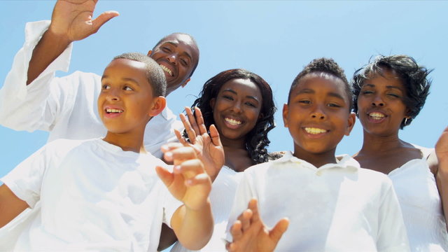 Close up of ethnic family skyping waving to camera on beach